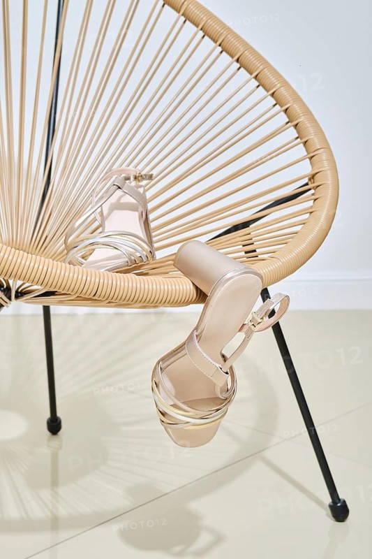 A pair of stylish beige high heel shoes elegantly placed on a modern wicker chair