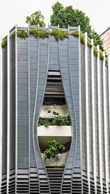This image captures a unique modern building in Singapore, featuring an architectural design that integrates green plants within its structure, highlighting urban sustainability