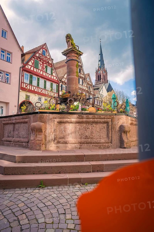 Historic fountain in an old town with church tower in the background, Calw, Black Forest, Germany