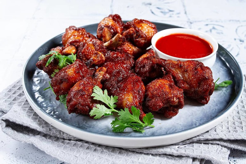 Crispy pieces of fried chicken, on a plate with sauce and herbs, in a modern kitchen environment, there are no people