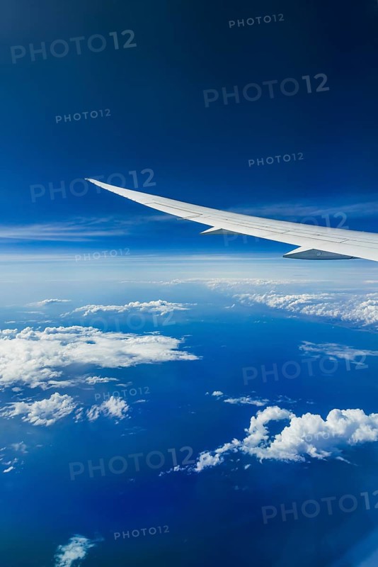 View from the aircraft window during a flight over India with the airline Etihad. Blue sky and cloud structures over the sea, wing of a Boeing 787 aircraft