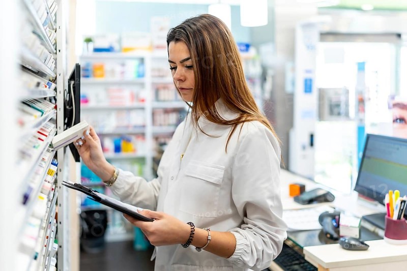 Pharmacist checking stock, organizing medication on shelves in a modern pharmacy, representing healthcare professional work, medicine management, and reliable service