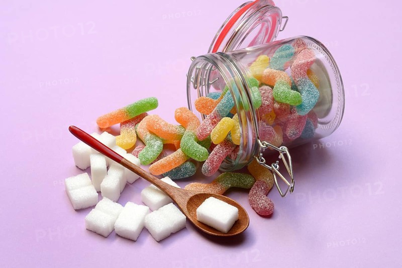 Lots of colorful jelly sweets in glass containers and sugar cubes, sugar consumption