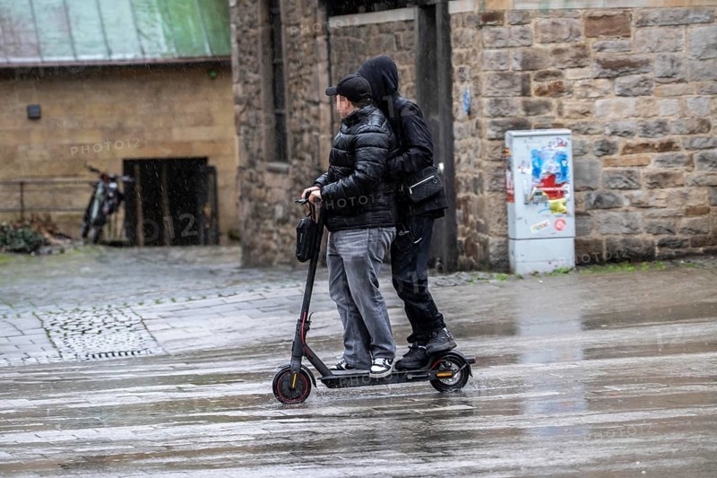 City center, shopping street, Kettwiger Straße pedestrian zone in Essen, 2 young men on an e-scooter, electric scooter, rainy weather, North Rhine-Westphalia, Germany