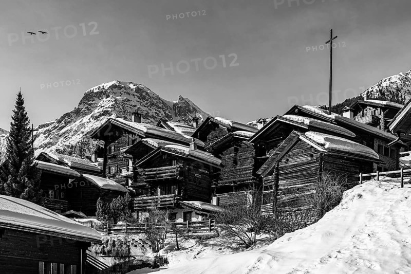 Snow-covered old farmhouses, large wooden cross, black and white photo, historic town center, Grimentz, Val d'Anniviers, Valais Alps, Canton of Valais, Switzerland