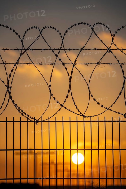 Symbolic image security at the airport, outer fence at Düsseldorf International Airport, steel wire fence, with S-wire rolls, NATO wire, on the top of the fence, aeroplane approaching, sunset, North Rhine-Westphalia, Germany