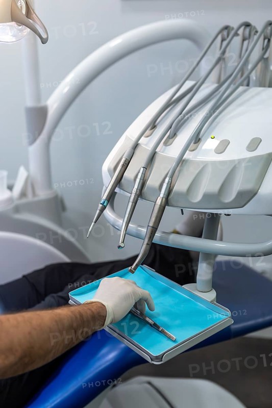 Close up of a dentist gloved hand reaching for a tool amidst advanced dental equipment. The image captures the essence of a contemporary dental practice