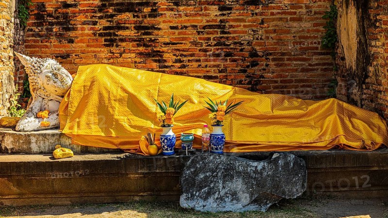 Reclining stone Buddha statue covered with yellow cloth, historic Buddhist temple complex, Ayutthaya, Thailand