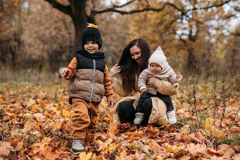 A joyful family enjoys an autumn day in the park, surrounded by colorful leaves. The warmth of the season creates a perfect backdrop for children playing and bonding with their parent