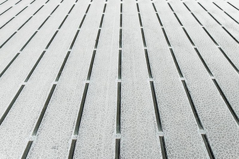 Close-up view of geometric salt formations at Salinas Grandes in Salta, Argentina. The surface displays linear patterns and natural salt crystal textures creating abstract symmetry