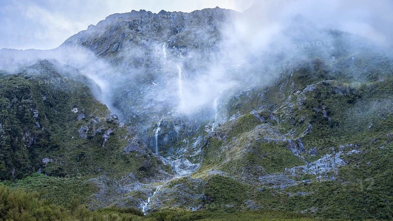Mountain landscape with waterfalls and clouds on Lake Marian. Fiordland National Park, Southland Region, South Island, New Zealand