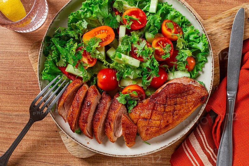 Delicious grilled duck breast served with fresh garden salad and cherry tomatoes at a rustic dining table
