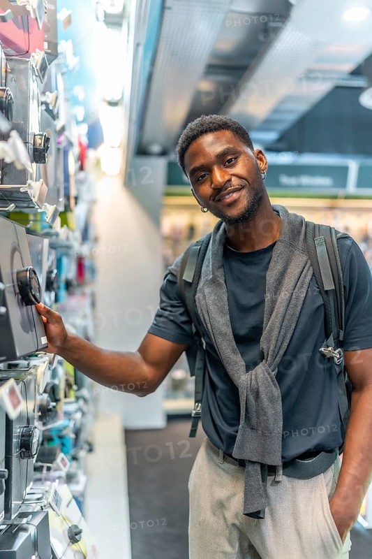 Vertical portrait of a handsome african young man in an electronics store