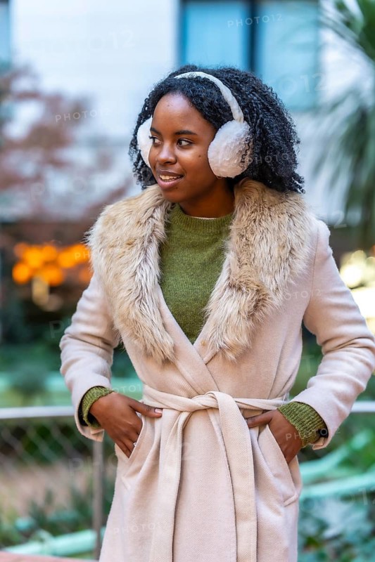 Smiling young woman wearing winter clothes and earmuffs enjoying a winter day in the city