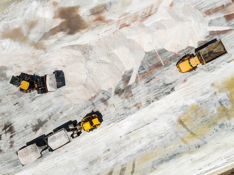 Excavator and lorries and at a harvesting pan of the Walvis Bay Salt works. Aerial view. Drone shot. Walvis Bay, Namibia