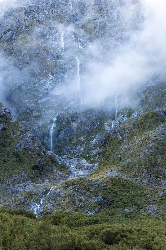 Mountain landscape with waterfalls and clouds on Lake Marian. Fiordland National Park, Southland Region, South Island, New Zealand