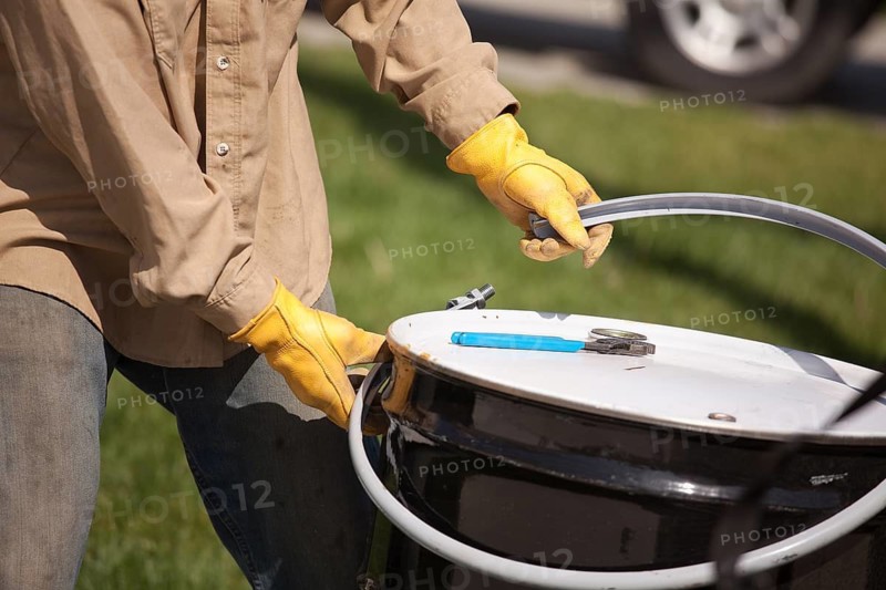 Utility Worker with Leather Gloves Opening or Sealing Oil Drum