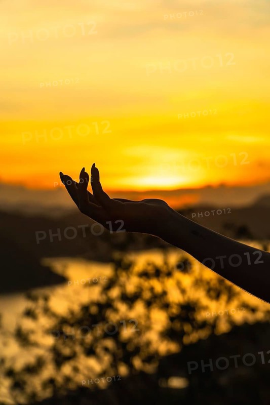 Woman's hand silhouette holding the setting sun at mount tapyas, coron island, philippines, creating a captivating travel image