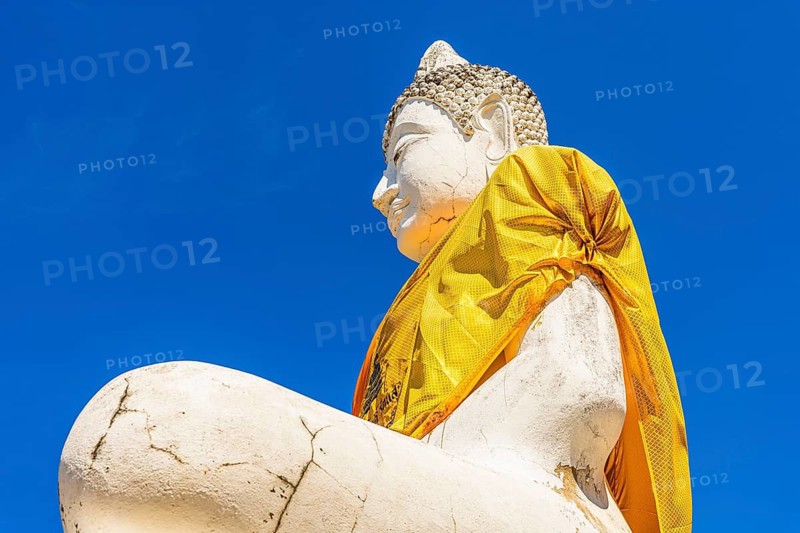 Stone Buddha statue decorated with yellow cloth, historic Buddhist temple complex, Ayutthaya, Thailand