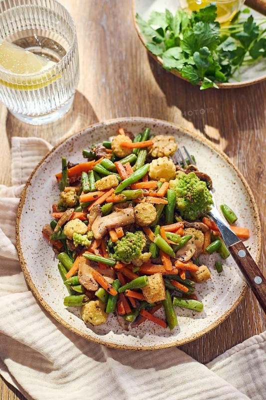 Plate of stir-fried mixed vegetables with green beans, carrots, baby corn, romanesco and mushrooms