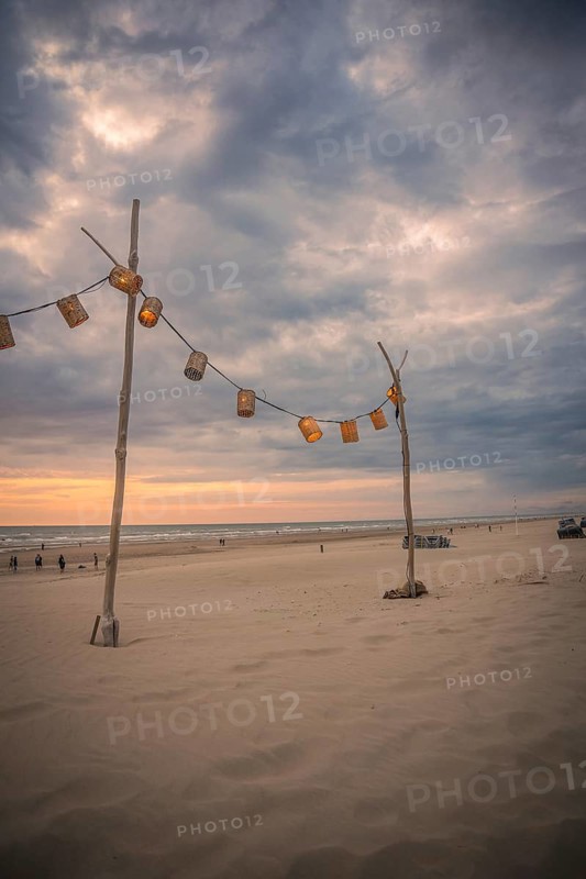 String of lights on wooden post on beach at sunset, Zandvoort, Netherlands