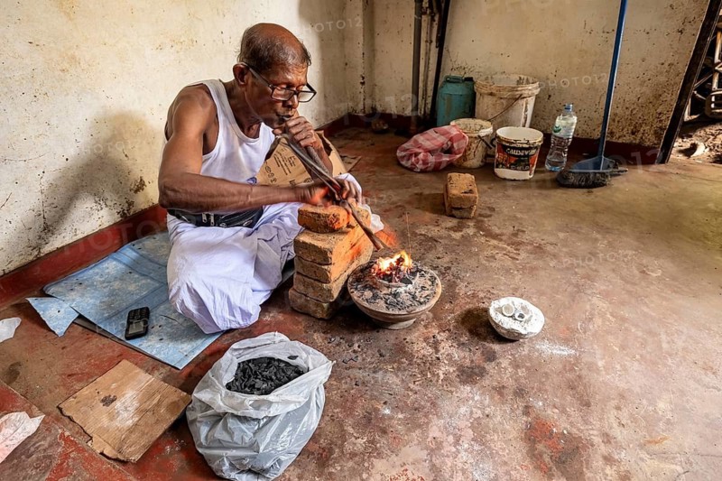Man in a workshop working concentrated with a blowpipe and bricks, a man burns sapphires in a small oven in the town of Ratnapura in Sri Lanka