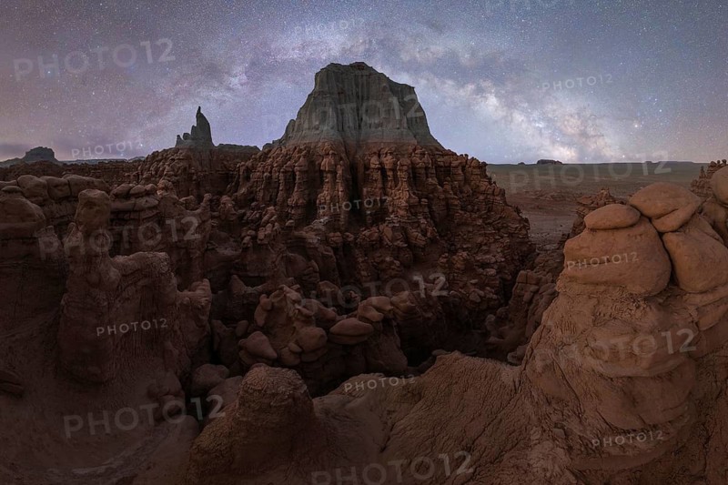 A mesmerizing panorama showing the Milky Way arcing above the unique rock formations of Goblin Valley State Park in Utah's desert landscape