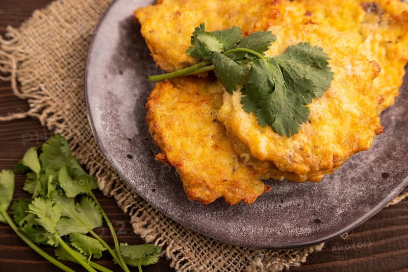 Fried crispy Chicken pancakes on brown wooden background and linen textile. side view, close up, selective focus