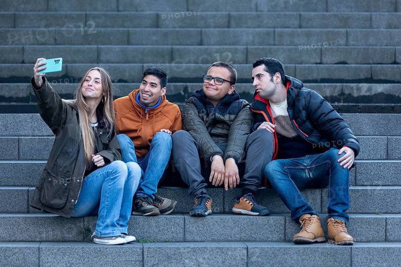 A caregiver and three young men with intellectual disabilities take a fun selfie in an urban setting