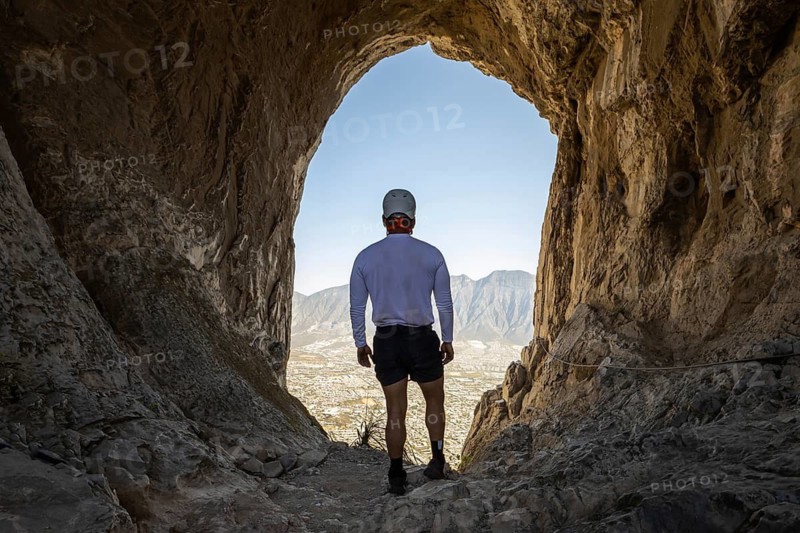 A man takes a break while mountaineering and rappelling at Eagle's Nest, Monterrey, Mexico, enjoying the magnificent view of the rugged mountain range and clear sky