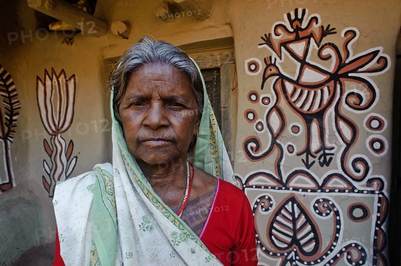 Portrait of a low caste woman in front of her house, Sohraï art (Hazaribagh district, Jharkhand, India) . The Sohraï and Khovar art are art forms practised by the rural low caste and tribal women in the Hazaribagh district. Every october-november, they paint their house mud walls to welcome the harvest and celebrate the cattle. These paintings depict animals and plants of the surroundings in a simple way