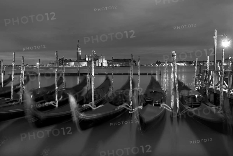 Nocturnal atmosphere with moving gondolas, San Georgio Maggiore in the back, Guidecca island on the right, black and white, Venice, Italy
