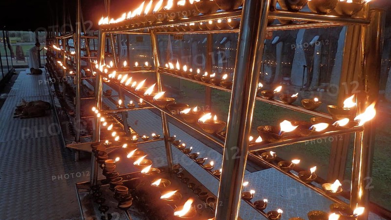 Rows of burning oil lamps at a spiritual ceremony create a mystical atmosphere in front of a temple, Sri Lanka