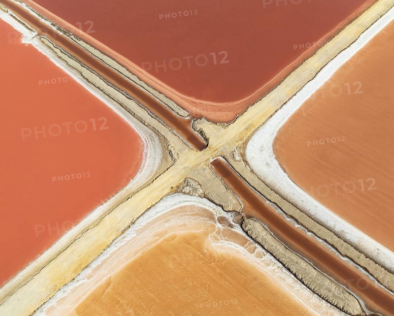 Saline ponds at the Bonanza salt works near Sanlúcar de Barrameda. The reddish colour depends on the level of salinity and is directly caused by the algae Dunaliella salina and brine shrimp. Aerial view. Drone shot. Cádiz province, Andalusia, Spain
