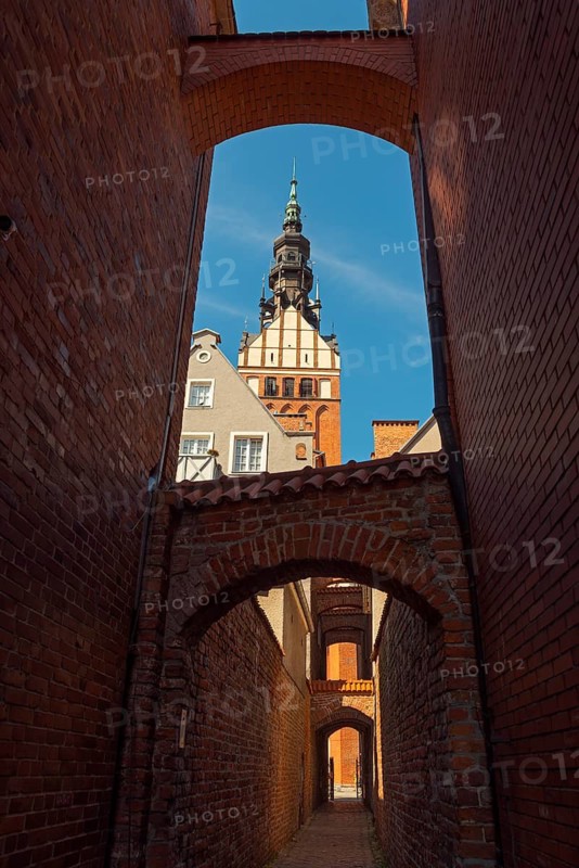 View through a passage to a Gothic church tower on a clear day, St Nicholas' Church, 13th century church path, Elblag, Elbing, Warminsko-Mazurskie Voivodeship, Warminsko-Mazurskie, Poland