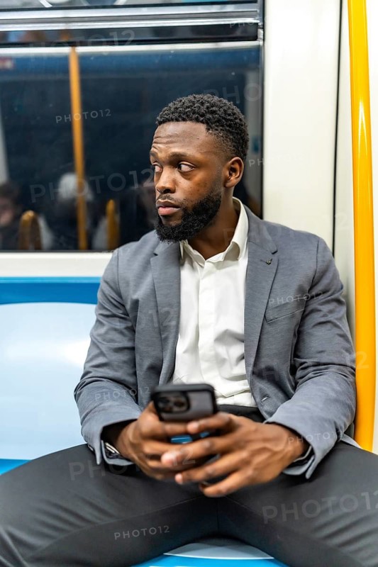 Young businessman commuting on a subway train, using a smartphone to stay connected and engaged with his work during the journey