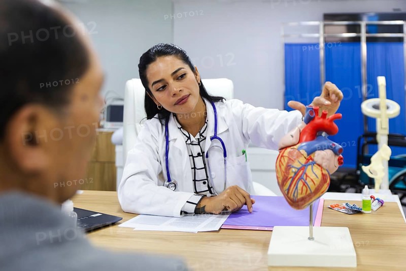 A caring young female doctor attends to an elderly male patient in a warm and professional Latin American hospital setting, showcasing attentive healthcare and patient interaction