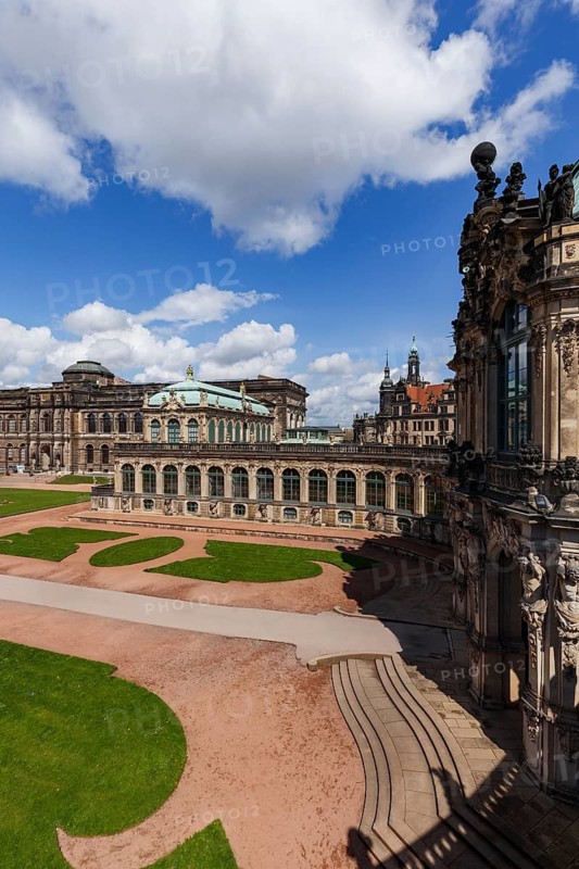 The Zwinger Palace in Dresden, Germany, showcases intricate Baroque architecture. The expansive courtyard and ornate details are highlighted under a bright, cloud-dotted sky