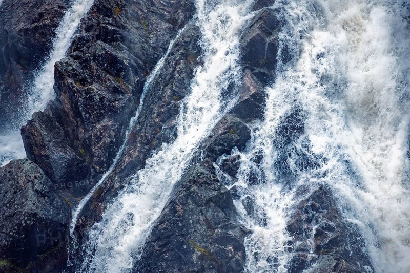 Detailed view of water cascading over rocky surfaces at Presa del Villar, Madrid, capturing the motion blur of flowing water