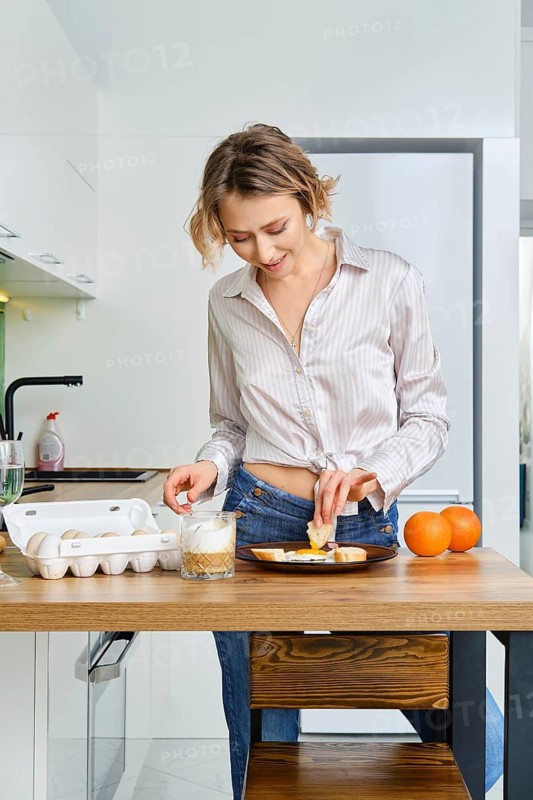 Young woman dips toast in fried egg
