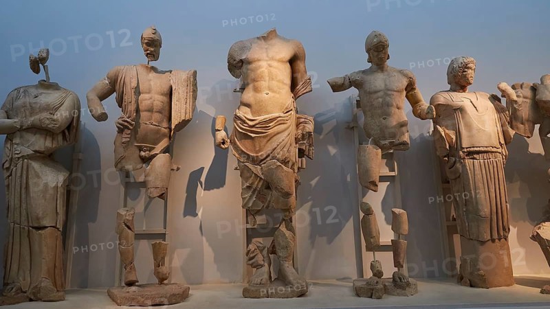 From left to right: Sterope, wife of Oinomaos, Oinomaos with helmet and spear, father of the gods Zeus, Prince Pelops, Hippodameia, east pediment of Zeus Temple, preparations for the chariot race between Pelops Oinomaos, fragmented ancient Greek marble statues, torses of various figures, Olympia Archaeological Museum, Ancient Olympia, Olympia, Peloponnese, Greece