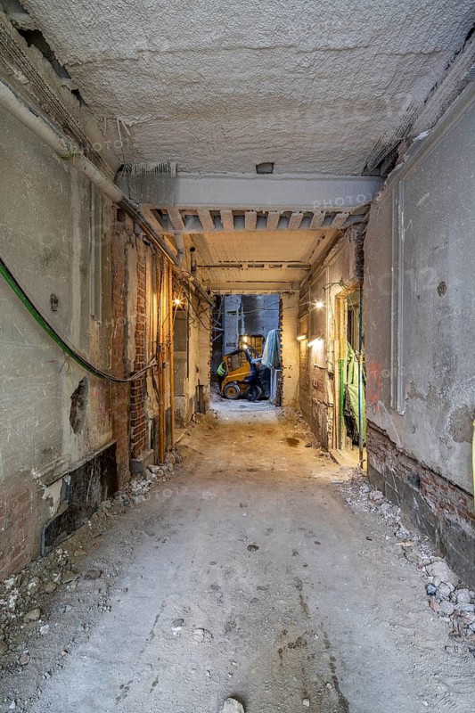 Industrial construction site interior under renovation. Exposed bricks, wires, and machinery create an authentic work-in-progress atmosphere, highlighting the transformation process