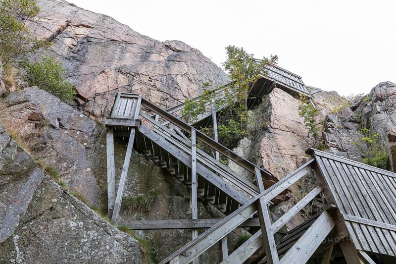 The rock wall rises vertically to the Kungsklyfta divide in Vetteberg, wooden stairs lead up, Fjällbacka, Västra Götalands län, Sweden