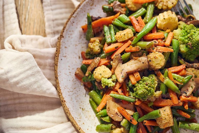 Plate of stir-fried mixed vegetables with green beans, carrots, baby corn, romanesco and mushrooms