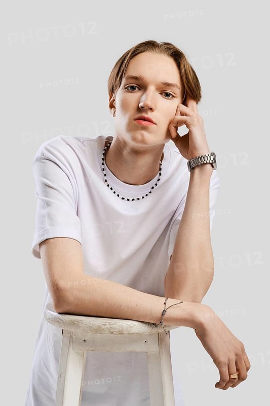 Closeup portrait of pensive young man in white t-shirt over grey studio background