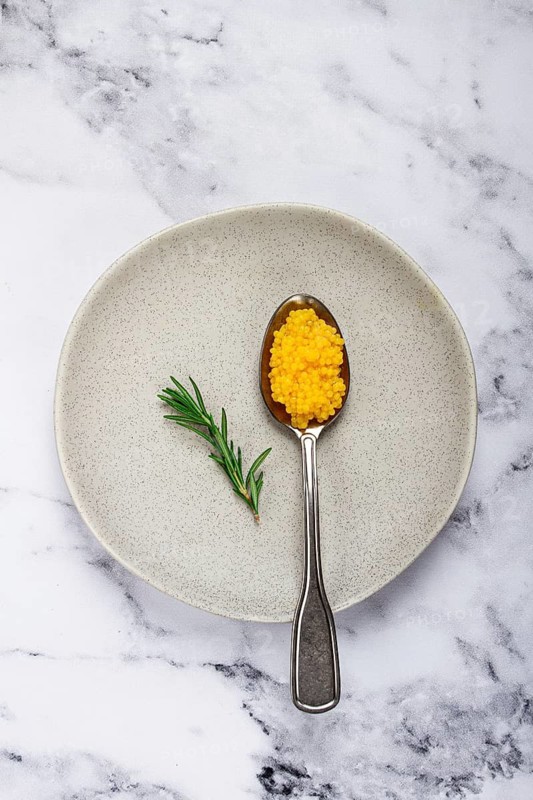 Yuzu caviar is pearly, on a spoon, top view, light background, no people