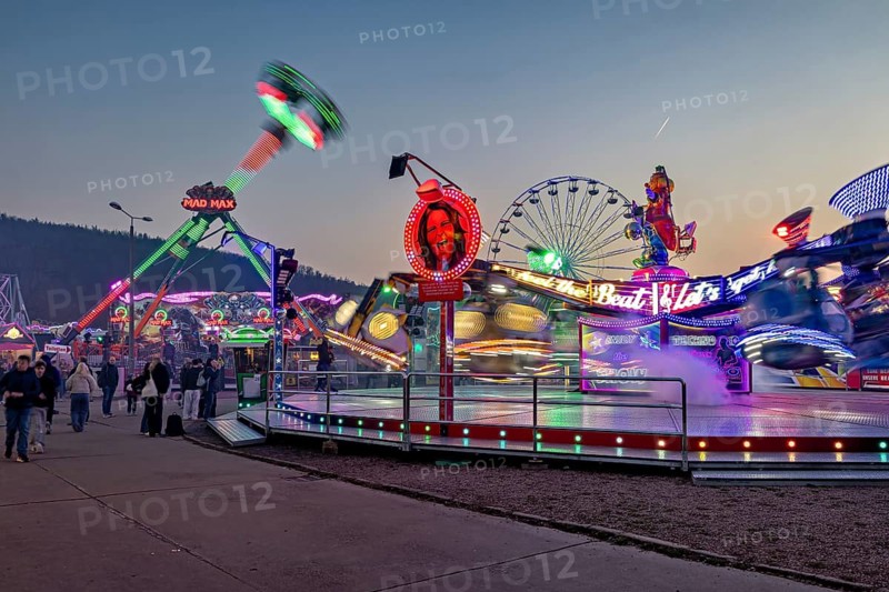 Moving rides and colorful lights at a busy fair at dusk, carousel and hustle and bustle of summer profit in Eisenach