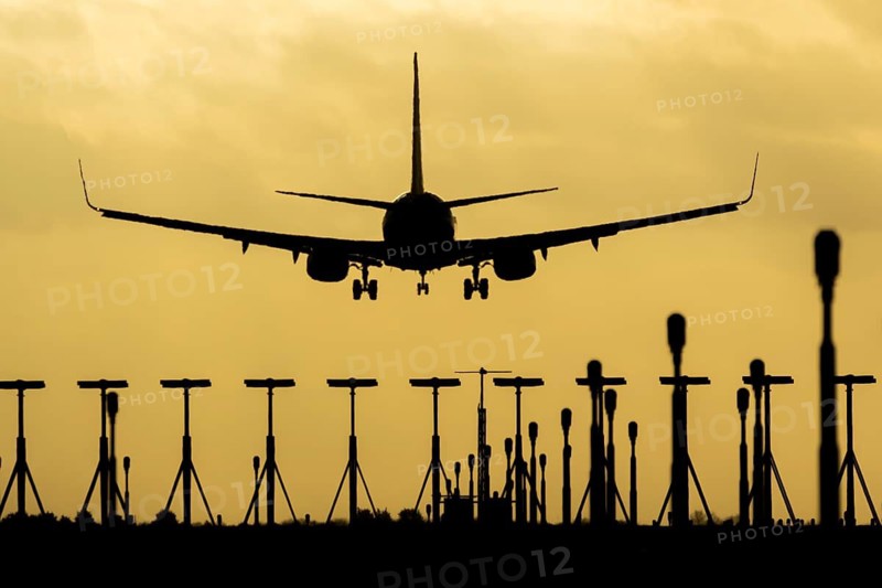 Boeing 737 commercial passenger airliner jet aircraft of Ryanair airways in flight on approach to land over runway lights at sunset at London Stansted airport, Essex, England, United Kingdom