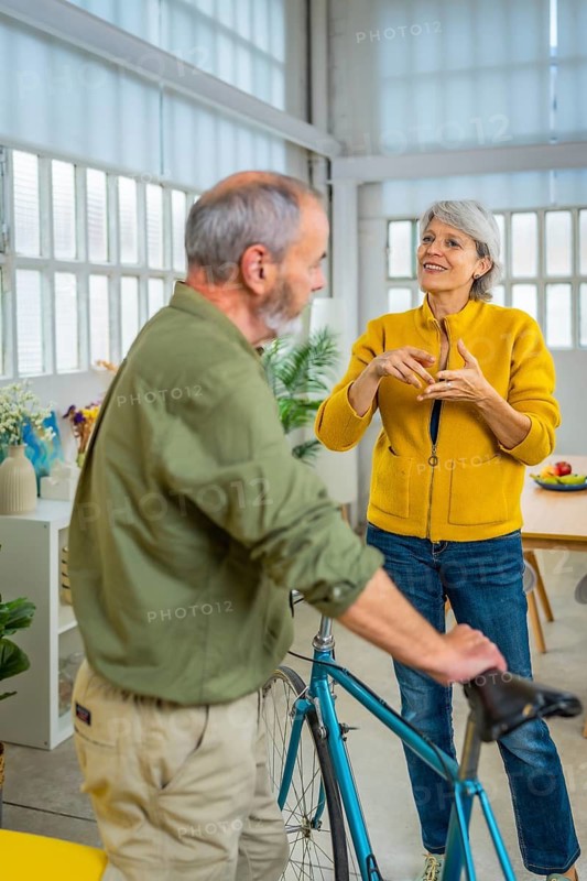 Vertical photo of a man holding a bike inside the house talking with his wife