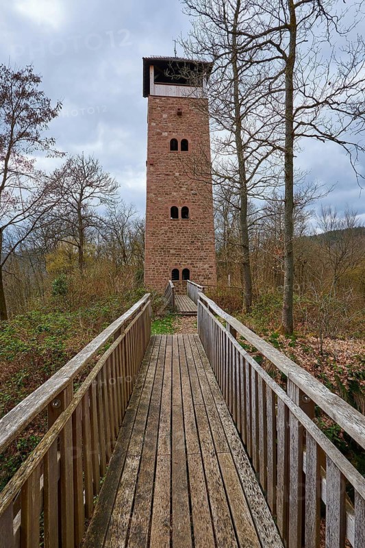 A stone tower rises majestically at the end of a wooden path surrounded by forest and dramatic sky, Ohrsberg Tower, Eberbach, Odenwald, Rhein-Neckar district, Baden-Württemberg, Germany